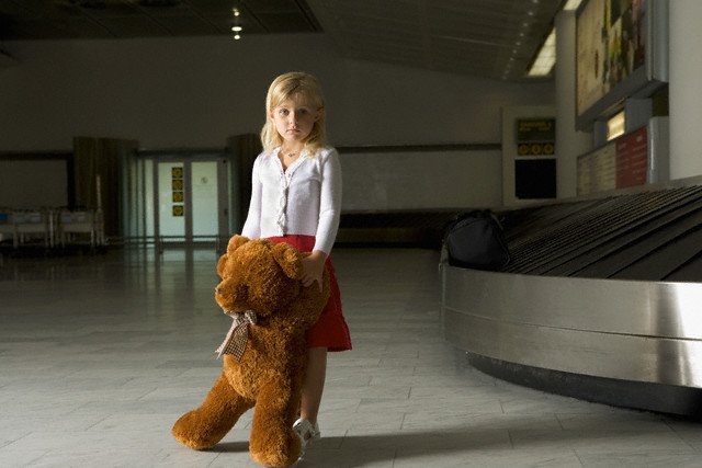 Girl with teddybear standing alone at the airport