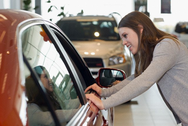 Young Woman Looking at a New Car